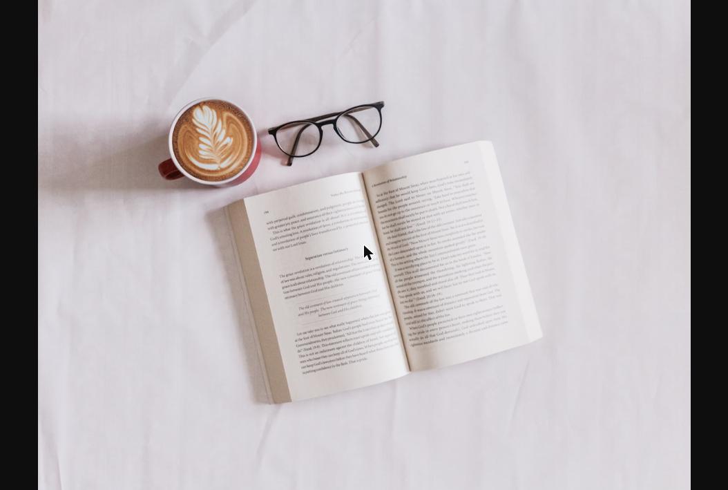Livro aberto com café e óculos de leitura